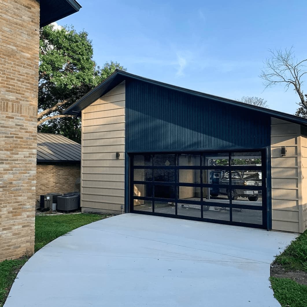 Full-view glass garage door with a black aluminum frame on a modern detached garage