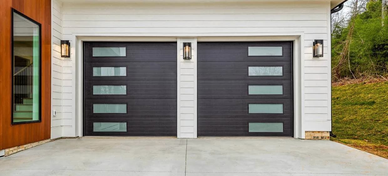 CHI Planks series garage doors in black with vertical rows of frosted glass on a modern home