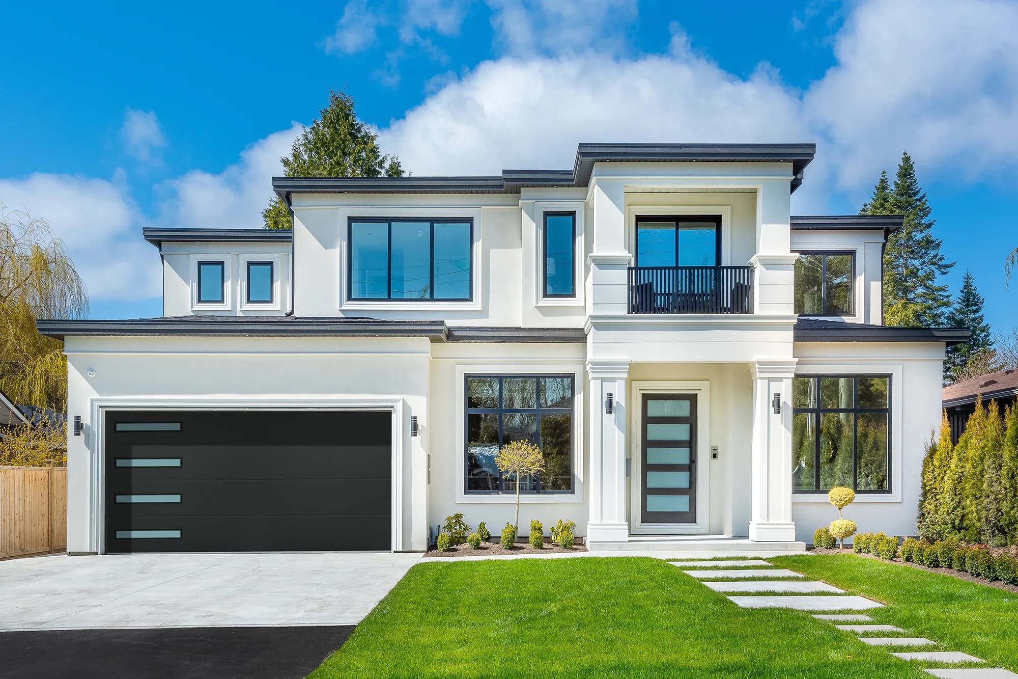 Black flush garage door with a horizontal window strip on a white modern two-story home