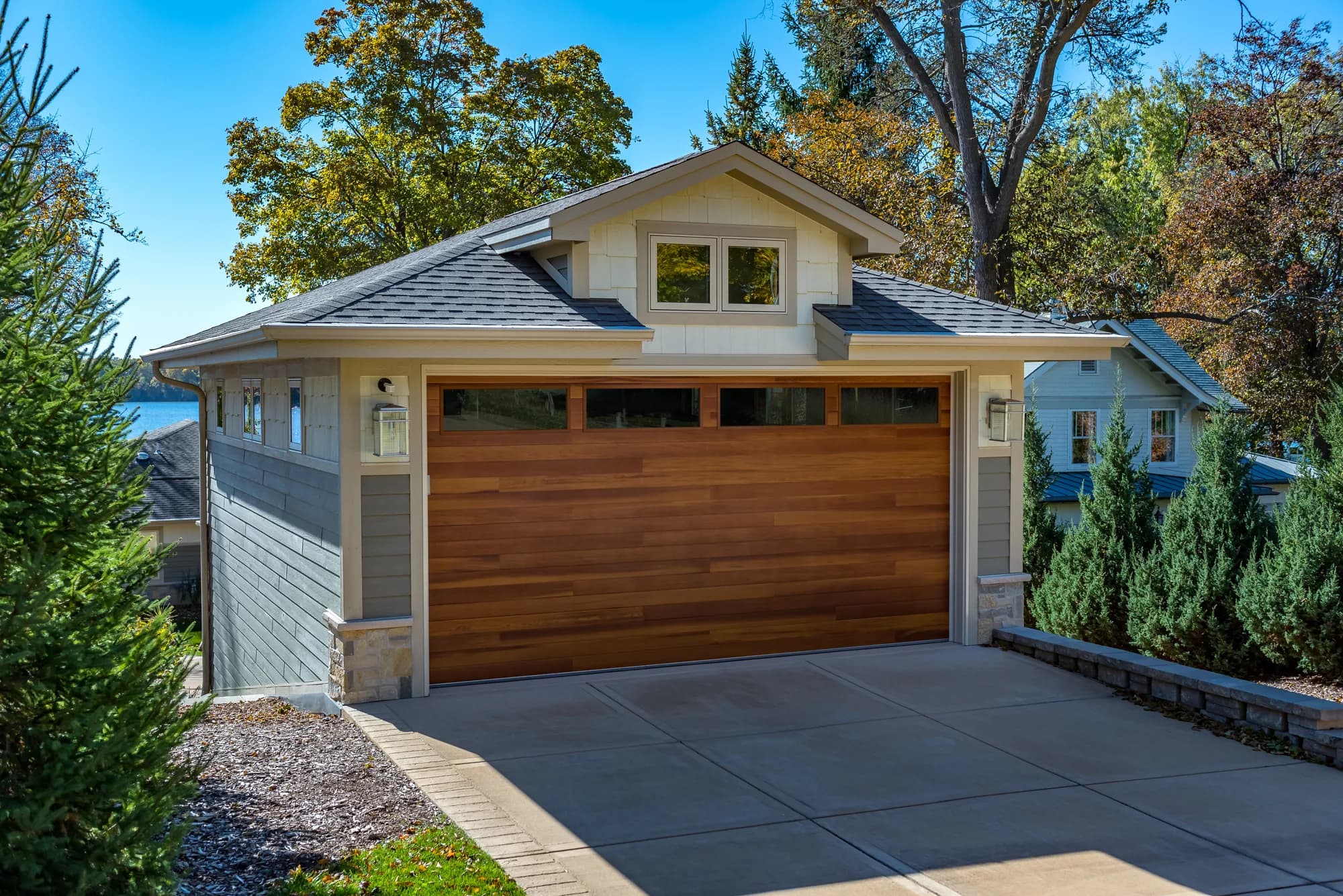 Cedar-tone horizontal plank garage door with a row of top windows on a grey craftsman garage
